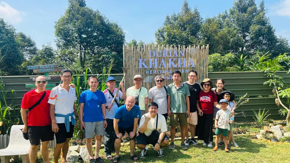 到访团在榴莲咔咔传承农场招牌前合影